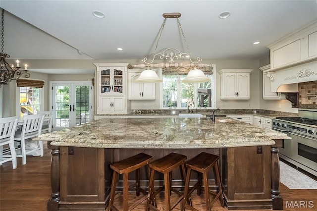 14703 Kulkarni Ct, Chesterfield, MO 63017 - kitchen featuring range with two ovens, light stone counters, recessed lighting, a kitchen island with sink, and pendant lighting