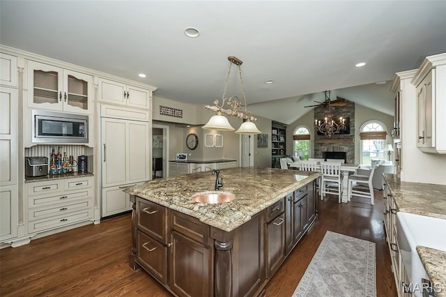 14703 Kulkarni Ct, Chesterfield, MO 63017 - kitchen with stainless steel microwave, ceiling fan, dark brown cabinetry, dark wood-style flooring, and vaulted ceiling