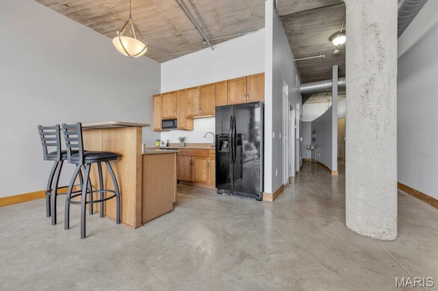 2323 Locust St Unit 405, Saint Louis, MO 63103 - kitchen featuring black appliances, finished concrete flooring, a kitchen breakfast bar, decorative light fixtures, and brown cabinets