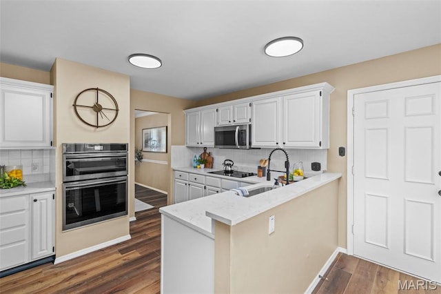 17 Beaujolais Dr, Florissant, MO 63031 - kitchen with stainless steel appliances, tasteful backsplash, dark wood finished floors, and white cabinetry