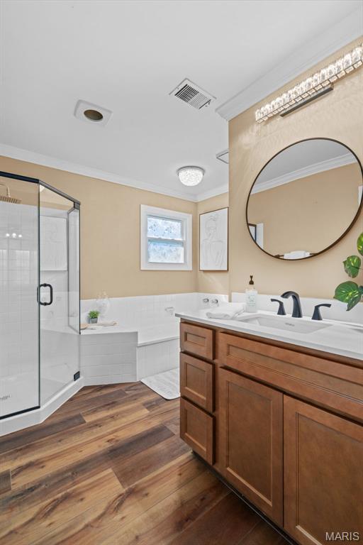 17 Beaujolais Dr, Florissant, MO 63031 - bathroom with ornamental molding, double vanity, a bath, a shower stall, and wood finished floors
