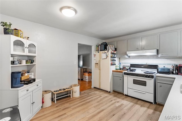 432 N 9th St, Mascoutah, IL 62258 - kitchen featuring white appliances, under cabinet range hood, light countertops, light wood finished floors, and backsplash