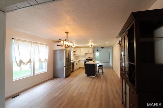 1001 E 2nd St, Saint Peter, IL 62880 - kitchen featuring appliances with stainless steel finishes, light wood-style floors, light countertops, a breakfast bar area, and backsplash
