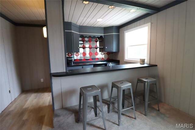 1001 E 2nd St, Saint Peter, IL 62880 - kitchen featuring dark countertops, wooden ceiling, wood walls, a breakfast bar area, and ornamental molding