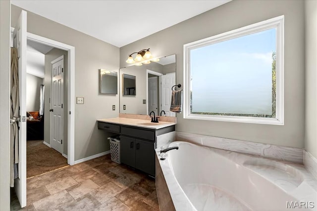 219 Royalltrail Ln, Saint Charles, MO 63368 - bathroom featuring vanity, a bath, healthy amount of natural light, and stone finish flooring