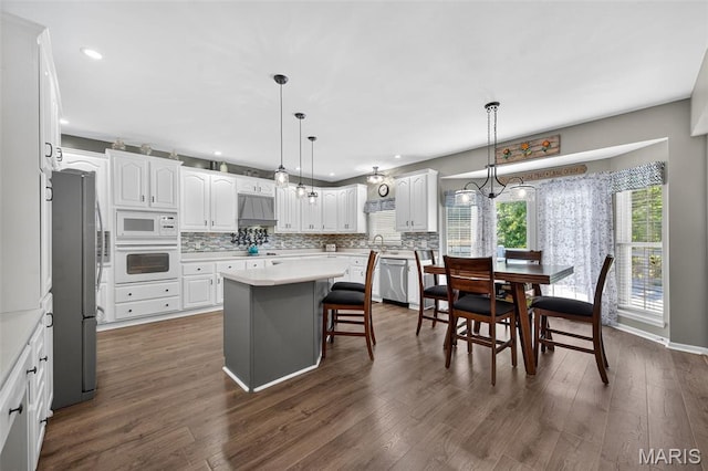 156 Bluffview Dr, Troy, MO 63379 - kitchen featuring appliances with stainless steel finishes, custom range hood, white cabinetry, backsplash, and a kitchen island
