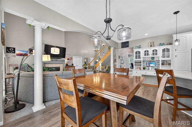 156 Bluffview Dr, Troy, MO 63379 - dining space with light wood-style flooring, stairs, a fireplace, and ornate columns