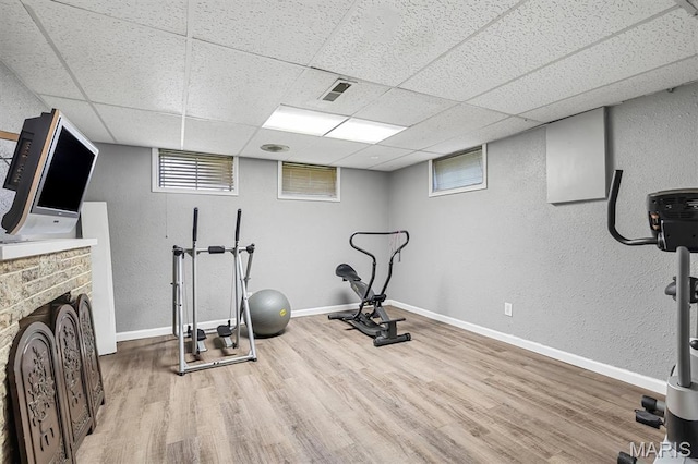 1326 Petite Dr, Saint Louis, MO 63138 - exercise area with wood finished floors, a textured wall, a paneled ceiling, plenty of natural light, and a fireplace
