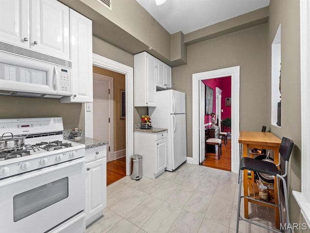 10 N Kingshighway Blvd Unit 4C, Saint Louis, MO 63108 - kitchen featuring white appliances, white cabinets, light marble finish flooring, and light stone counters