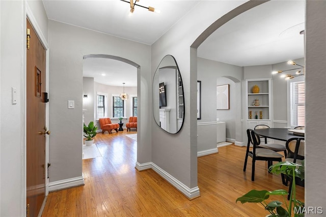 7801 Delmar Blvd Unit 2W, University City, MO 63130 - corridor featuring a chandelier, light wood-style floors, and arched walkways