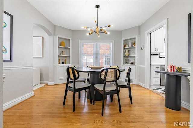 7801 Delmar Blvd Unit 2W, University City, MO 63130 - dining room featuring built in shelves, a chandelier, light wood finished floors, and arched walkways