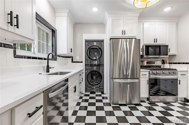7801 Delmar Blvd Unit 2W, University City, MO 63130 - kitchen featuring appliances with stainless steel finishes, stacked washer and clothes dryer, tile patterned floors, white cabinetry, and recessed lighting