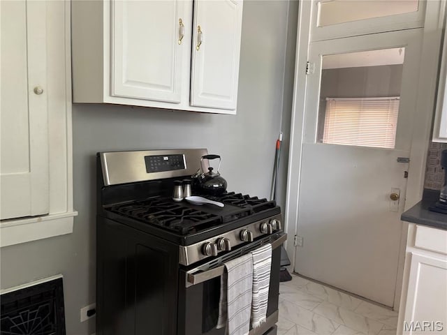 2425 State St, Granite City, IL 62040 - kitchen featuring gas range, light marble finish flooring, white cabinetry, and dark countertops