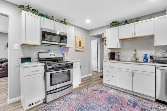 3711 Ashby Rd, Saint Ann, MO 63074 - kitchen featuring stainless steel appliances, light countertops, light wood-style floors, white cabinetry, and recessed lighting