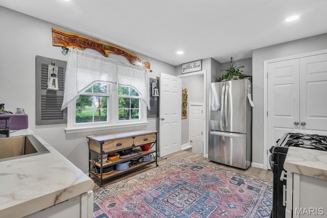 3711 Ashby Rd, Saint Ann, MO 63074 - kitchen with stainless steel refrigerator with ice dispenser, black gas stove, light wood-style floors, light stone countertops, and recessed lighting