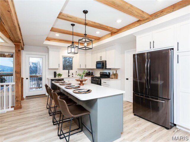 24925 State Route Mm, Farmington, MO 63640 - kitchen featuring black appliances, light wood-style floors, a kitchen bar, light countertops, and white cabinets