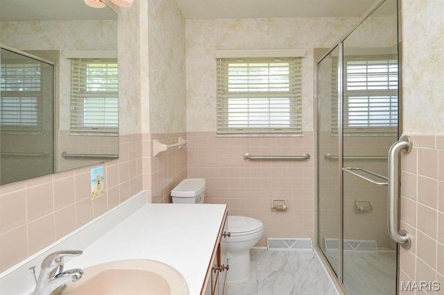 318 W Oak St, Mascoutah, IL 62258 - bathroom featuring tile walls, plenty of natural light, a shower stall, vanity, and a wainscoted wall