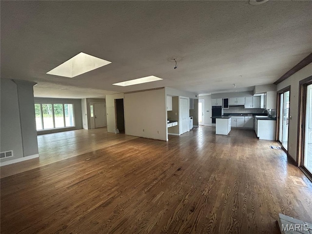 17300 W Bridle Trl, Wildwood, MO 63038 - unfurnished living room featuring a skylight, dark wood-style flooring, and a textured ceiling