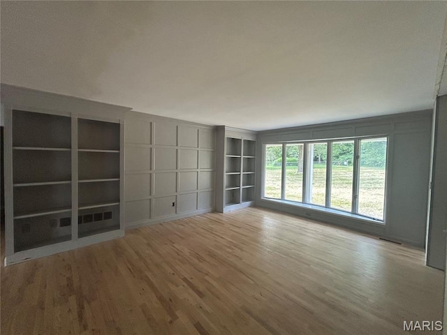 17300 W Bridle Trl, Wildwood, MO 63038 - unfurnished room with wood finished floors, built in shelves, and a decorative wall
