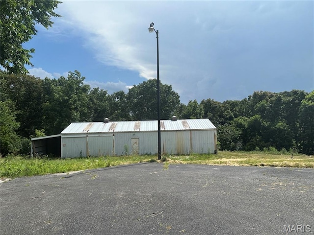 17300 W Bridle Trl, Wildwood, MO 63038 - view of asphalt road with street lighting, an outbuilding, and a view of trees