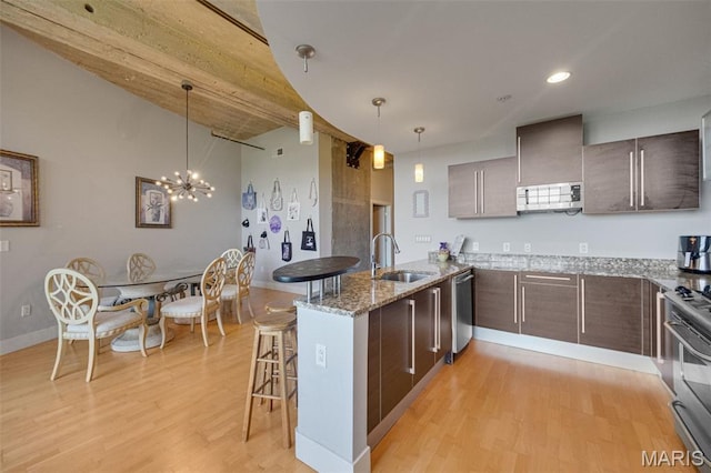 4100 Forest Park Ave Unit 306, Saint Louis, MO 63108 - kitchen with a peninsula, a breakfast bar area, stainless steel appliances, light wood-style flooring, and light stone countertops