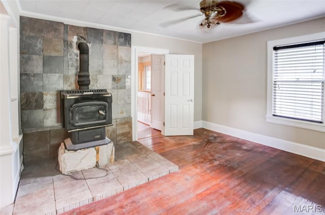 86 Mill St, Elsah, IL 62028 - unfurnished living room with a wood stove, a ceiling fan, plenty of natural light, ornamental molding, and wood finished floors