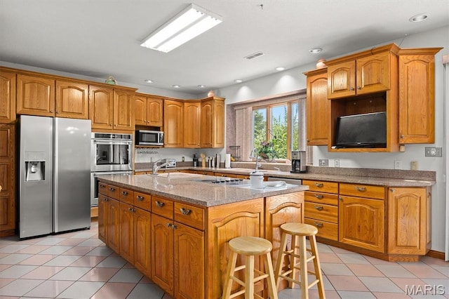 517 E Waters Edge Dr, Shiloh, IL 62221 - kitchen with appliances with stainless steel finishes, light stone countertops, a kitchen island with sink, brown cabinets, and recessed lighting