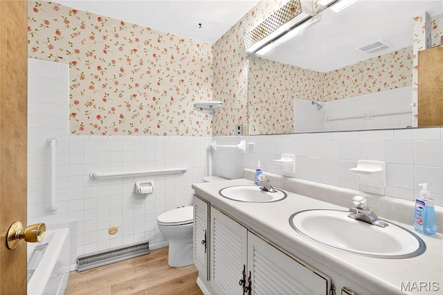 401 Willowbrook Ln, Collinsville, IL 62234 - bathroom featuring wallpapered walls, wood finished floors, tile walls, double vanity, and a tub to relax in