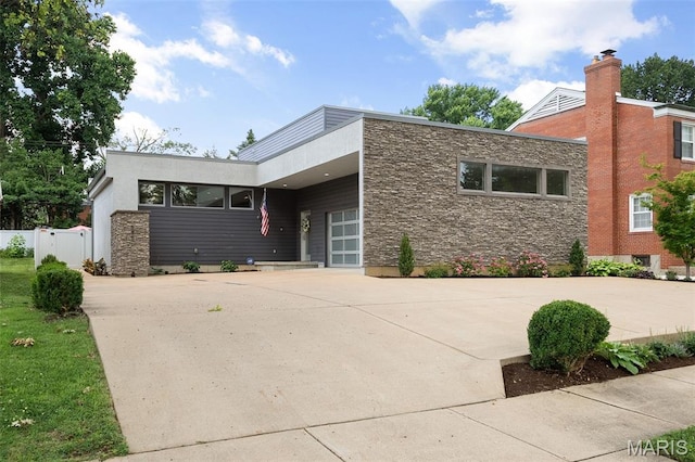 5951 Jamieson Ave, Saint Louis, MO 63109 - view of front facade with stone siding, concrete driveway, and an attached garage