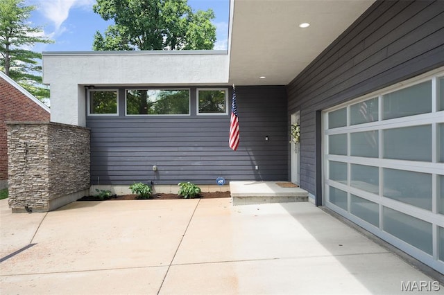 5951 Jamieson Ave, Saint Louis, MO 63109 - entrance to property featuring a garage, a patio, concrete driveway, and stucco siding