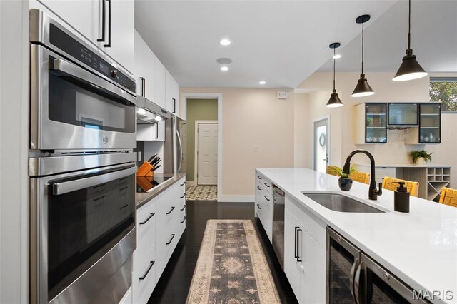 5951 Jamieson Ave, Saint Louis, MO 63109 - kitchen with stainless steel appliances, white cabinetry, light countertops, dark wood finished floors, and hanging light fixtures