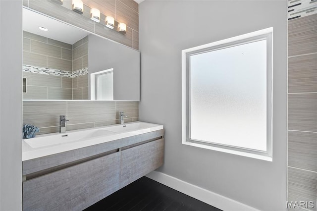 5951 Jamieson Ave, Saint Louis, MO 63109 - bathroom featuring double vanity, wood finished floors, and tasteful backsplash