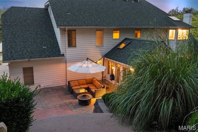 17527 Adams Way Ct, Wildwood, MO 63005 - back of property at dusk with an outdoor living space with a fire pit, a patio, a shingled roof, and a chimney