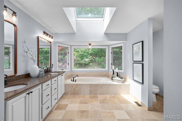 17527 Adams Way Ct, Wildwood, MO 63005 - full bathroom featuring a skylight, double vanity, a bath, and stone finish floors