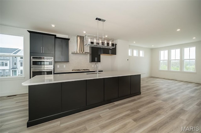 8935 E Gateway Hts Unit 94-808, Richmond Heights, MO 63144 - kitchen with wall chimney exhaust hood, stainless steel appliances, a large island, light countertops, and recessed lighting