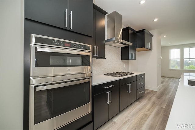 8935 E Gateway Hts Unit 94-808, Richmond Heights, MO 63144 - kitchen featuring wall chimney exhaust hood, stainless steel appliances, tasteful backsplash, light countertops, and light wood-type flooring