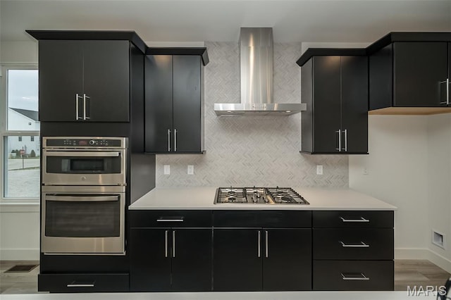 8935 E Gateway Hts Unit 94-808, Richmond Heights, MO 63144 - kitchen featuring wall chimney range hood, dark cabinetry, and stainless steel appliances