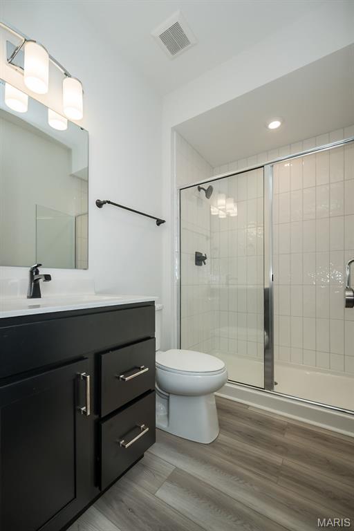 8935 E Gateway Hts Unit 94-808, Richmond Heights, MO 63144 - bathroom featuring vanity, a tile shower, and wood finished floors