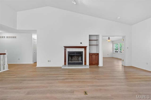 425 Charter Way Dr, Wildwood, MO 63040 - unfurnished living room featuring light wood finished floors, a tile fireplace, built in shelves, and high vaulted ceiling