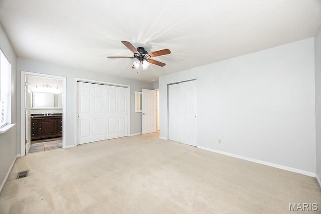 2313 College, Belleville, IL 62221 - unfurnished bedroom featuring two closets, light colored carpet, ensuite bath, and a ceiling fan