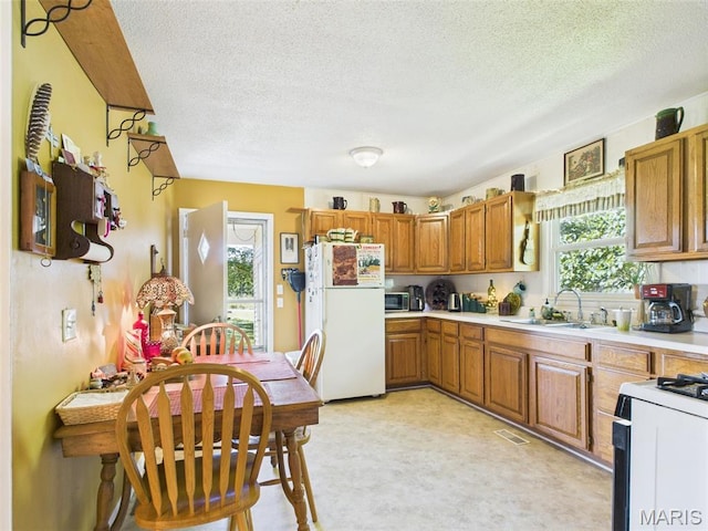 7603 Blue Moon Rd, Bucyrus, MO 65444 - kitchen featuring white appliances, light countertops, a textured ceiling, and brown cabinets