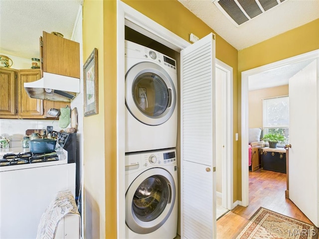 7603 Blue Moon Rd, Bucyrus, MO 65444 - laundry room with stacked washing machine and dryer, light wood-type flooring, and a textured ceiling