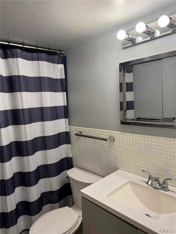 4229 Carrollton Dr Unit C, Bridgeton, MO 63044 - bathroom featuring vanity, tile walls, wainscoting, and curtained shower