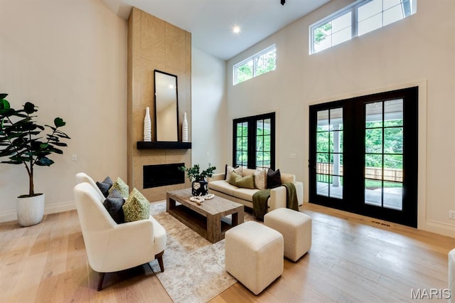 224 Oak Tree Dr, Webster Groves, MO 63119 - living room with french doors, light wood-style floors, a towering ceiling, and a fireplace
