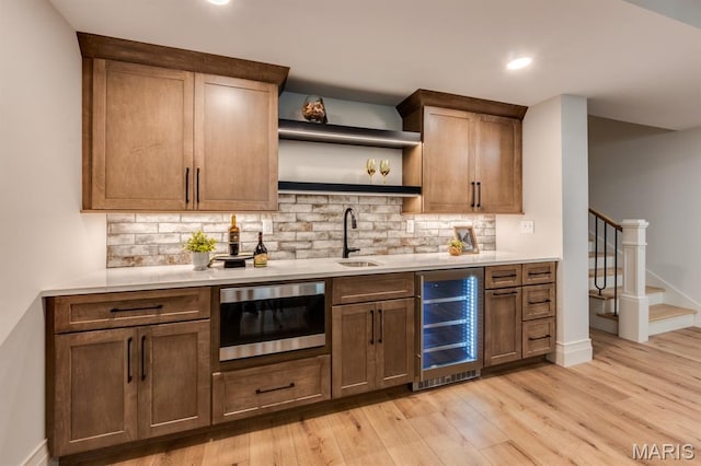 224 Oak Tree Dr, Webster Groves, MO 63119 - indoor wet bar with beverage cooler, stainless steel microwave, light wood-type flooring, stairs, and decorative backsplash