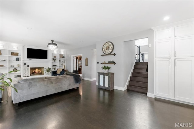 12429 Nicholas Ln, Saint Louis, MO 63131 - living area featuring stairs, a warm lit fireplace, dark wood-style flooring, built in features, and recessed lighting