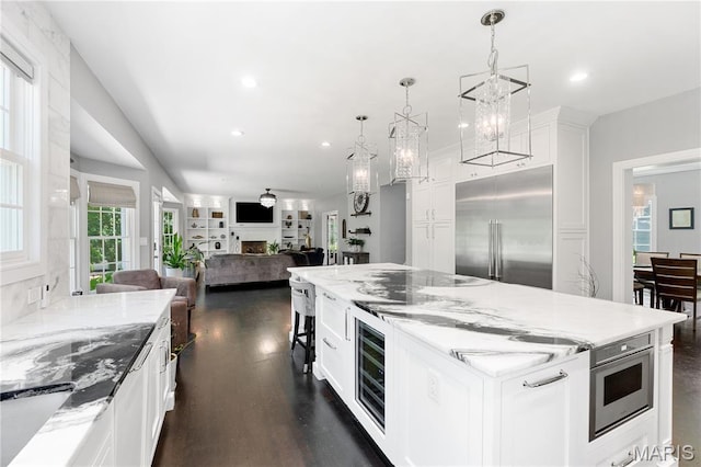 12429 Nicholas Ln, Saint Louis, MO 63131 - kitchen with built in fridge, white cabinetry, open floor plan, wine cooler, and light stone counters