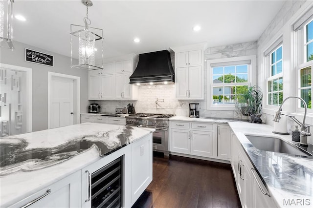 12429 Nicholas Ln, Saint Louis, MO 63131 - kitchen with custom exhaust hood, range with two ovens, beverage cooler, white cabinetry, and decorative backsplash