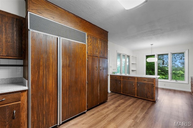 1938 State Highway Oo, Whitewater, MO 63785 - kitchen featuring paneled refrigerator, light wood-style floors, light countertops, backsplash, and decorative light fixtures
