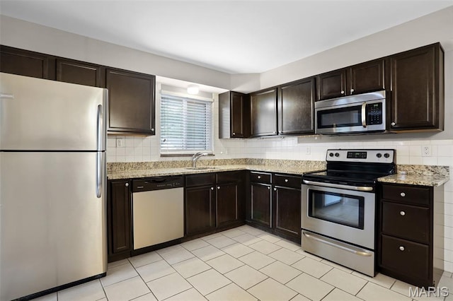 11380 Manchester Rd, Kirkwood, MO 63122 - kitchen with stainless steel appliances, backsplash, dark brown cabinets, light stone counters, and light tile patterned flooring